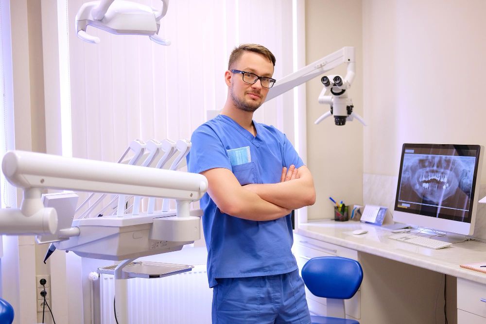 portrait-handsome-dentist-wearing-blue-uniform-standing-dentist-clinic-looking-camera
